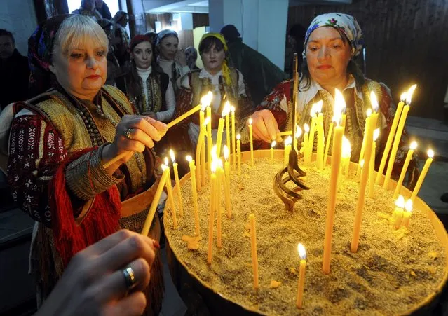 Women dressed in traditional folk costume light candles during an Epiphany day celebration in Bitushe village, about 150km (93 miles) west from the capital Skopje, January 19, 2015. Bitushe practises a different Epiphany tradition. (Photo by Ogenen Teolovski/Reuters)