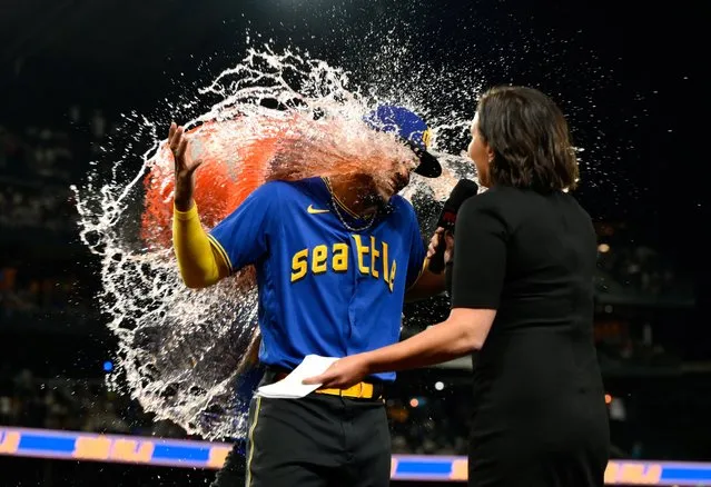 Seattle Mariners right fielder Teoscar Hernandez (rear) dumps the water jug on center fielder Julio Rodriguez (44) while being interviewed by TV personality Jen Mueller after the game against the Baltimore Orioles at T-Mobile Park in Seattle, Washington on August 11, 2023. (Photo by Steven Bisig/USA TODAY Sports)
