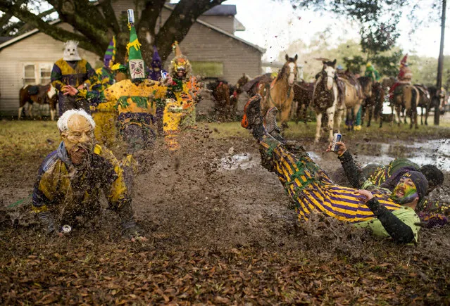 Costumed participants splash in a mud puddle while awaiting the Courir de Mardi Gras in Mamou, La., Tuesday, February 17, 2015. Courir participants travel through the town, begging homeowners for ingredients to create a large community gumbo, while chasing chickens as part of the holiday tradition. (Photo by Paul Kieu/AP Photo/The Lafayette Daily Advertiser)