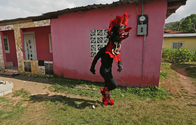 A man dressed in a devil costume walks home to take a break from the Devils and Congos carnival ritual, in Nombre de Dios, Panama, Wednesday, February 18, 2015. (Photo by Arnulfo Franco/AP Photo)