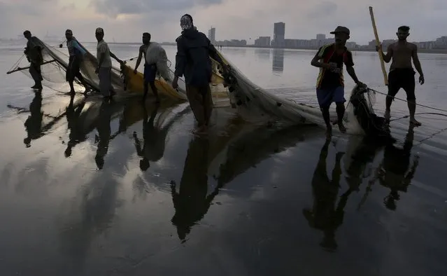 Pakistani fishermen drag their nets while they leave after catching fishes in sea at the beach in Karachi, Pakistan, Saturday, May 29, 2021. (Photo by Fareed Khan/AP Photo)