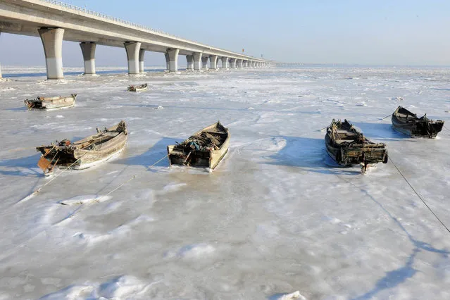 Row boats sit stuck in the ice of the frozen coastal waters of Jiaozhou Bay in Qingdao in eastern China's Shandong province on January 25, 2016. Snow, sleet and icy winds across Asia caused deaths, flight cancellations and chaos over the weekend as areas used to basking in balmier climates struggled with record-low temperatures. (Photo by AFP Photo/Stringer)