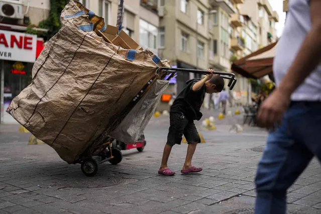 A young trash collector pulls a trolley full of cardboards at Kadikoy neighbourhood in Istanbul, Turkey, Wednesday, September 27, 2023. (Photo by Francisco Seco/AP Photo)