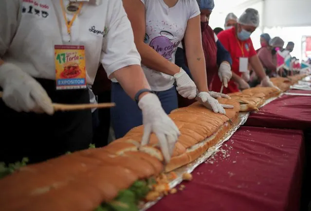 Workers and exhibitors cut a giant Torta of 74.2 meters long during the Torta fair, attempting at the world's largest sandwich (commonly called Torta in Mexico), in Mexico City, Mexico on August 3, 2022. (Photo by Henry Romero/Reuters)