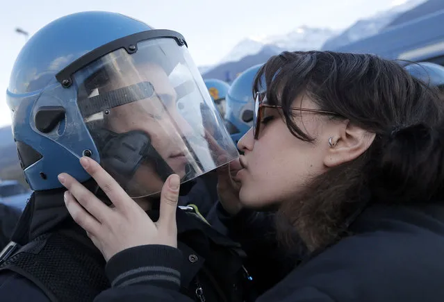 A demonstrator kisses a riot police officer on November 16, 2013 during a protest in Susa against the high-speed train (TAV in Italian) line between Lyon and Turin. The link, expected to come into service in 2025, will see one million fewer trucks on the highways a year, and reduce train times between Paris and Milan from seven hours to just over four. (Photo by Marco Bertorello/AFP Photo)