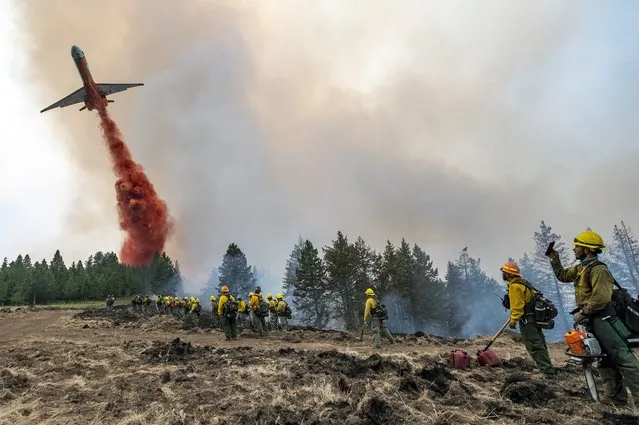 Wildland firefighters watch and take video with their cellphones as a plane drops fire retardant on Harlow Ridge above the Lick Creek Fire, southwest of Asotin, Wash., Monday, July 12, 2021. The fire, which started last Wednesday, has now burned over 50,000 acres of land between Asotin County and Garfield County in southeast Washington state. (Photo by Pete Caster/Lewiston Tribune via AP Photo)