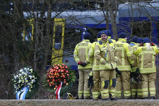 Rescue workers stand besides wreaths in front of two trains that collided head-on near Bad Aibling, Germany,  Wednesday, February 10, 2016. At least ten people have been killed and dozens were injured in the accident. (Photo by Matthias Schrader/AP Photo)