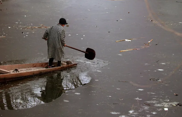 A boy uses his oar to break ice to move his boat on the frozen Anchar Lake on a cold winter day in Srinagar December 27, 2018. (Photo by Danish Ismail/Reuters)