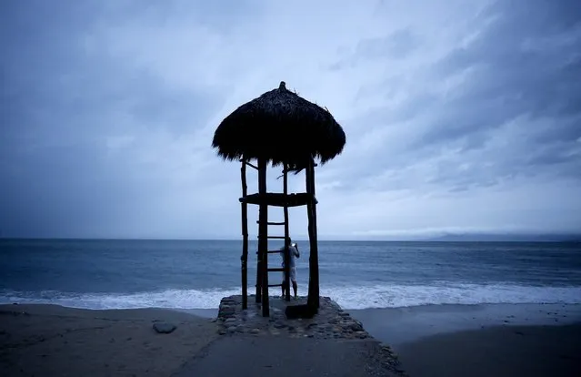 A man takes pictures under a beach lifeguard watch hut in Puerto Vallarta, Jalisco State, Mexico, on October 10, 2023, as Hurricane Lidia came ashore near this popular beach resort in the Mexican Pacific coast. Hurricane Lidia made landfall Tuesday on Mexico's Pacific coast as an “extremely dangerous” Category 4 storm, threatening to bring flooding and mudslides, forecasters said. President Andres Manuel Lopez Obrador said earlier that civil protection personnel were on alert and around 6,000 members of the armed forces had been deployed to help residents. (Photo by Ulises Ruiz/AFP Photo)