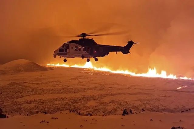 This image made from video provided by the Icelandic Coast Guard shows its helicopter flying near magma running on a hill near Grindavik on Iceland's Reykjanes Peninsula sometime around late Monday, December 18, or early Tuesday, December 19, 2023. A volcanic eruption started Monday night on Iceland's Reykjanes Peninsula, turning the sky orange and prompting the country’s civil defense to be on high alert. (Photo by Icelandic coast guard via AP Photo)