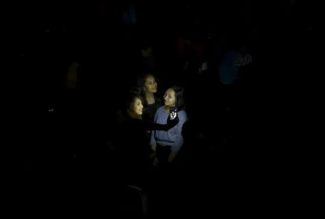 A flash illuminates girls taking a group selfie during the Bisket festival in Bhaktapur April 13, 2015. The festival, which runs for more than a week and coincides with the Nepalese New Year, involves devotees offering prayers and the pulling of two chariots, one bearing the idol of God Bhairab and the other with the idol of Goddess Bhadrakali, around the ancient city of Bhaktapur. (Photo by Navesh Chitrakar/Reuters)