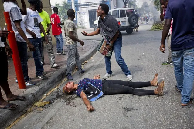 A demonstrator asks for help for a woman who was shot during clashes with national police officers, as they demanded the resignation of President Jovenel Moise and demanding to know how Petro Caribe funds have been used by the current and past administrations, in Port-au-Prince, Haiti, Thursday, February 7, 2019. Much of the financial support to help Haiti rebuild after the 2010 earthquake comes from Venezuela's Petro Caribe fund, a 2005 pact that gives suppliers below-market financing for oil and is under the control of the central government. (Photo by Dieu Nalio Chery/AP Photo)