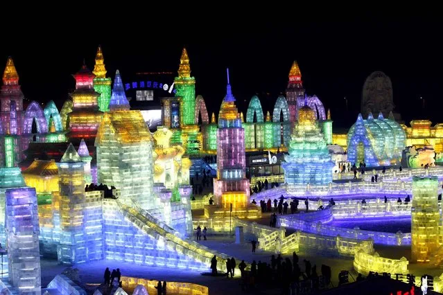 This picture taken on December 30, 2013 shows people visiting the ice lanterns and carvings of the 2014 Harbin International Ice and Snow Festival in Harbin, in northeast China's Heilongjiang province. This year's “Ice and Snow World” will officially open on January 5, 2014. (Photo by AFP Photo)
