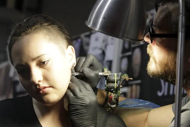 An artist draws a tattoo on a woman's neck during a tattoo convention in Ljubljana April 18, 2015. (Photo by Srdjan Zivulovic/Reuters)