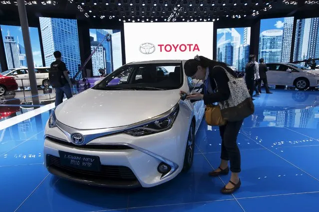 A woman takes pictures of a Toyota Levin HEV car during the 16th Shanghai International Automobile Industry Exhibition in Shanghai, April 20, 2015. Foreign automakers continue to plough money into factories in China, the world's largest car market, even as the biggest economic slowdown in a quarter of a century crimps sales growth. (Photo by Aly Song/Reuters)