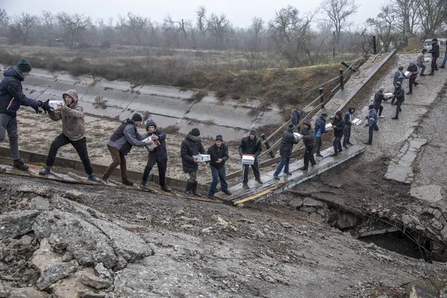 Locals help transferring humanitarian aid across a collapsed bridge near Novopetrivka, following the withdrawal of Russian troops from Kherson region, Ukraine, November 17th, 2022. (Photo by Narciso Contreras/Anadolu Agency via Getty Images)