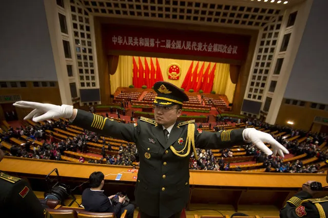 A Chinese military band conductor leads the band at the end of the opening session of the annual National People's Congress in Beijing's Great Hall of the People, Saturday, March 5, 2016. China's leadership tried to quell anxiety about its slowing economy following financial turmoil and rising labor unrest as it cut its growth target Saturday and promised to open oil and telecoms industries to private competitors in sweeping industrial reforms. (Photo by Ng Han Guan/AP Photo)