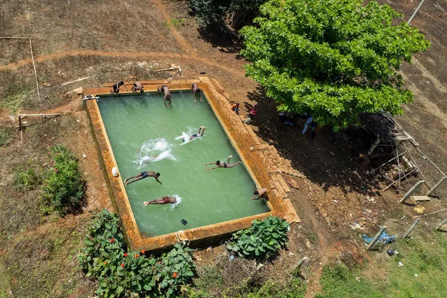 In this aerial photograph taken on October 4, 2021, boys dive in an open water tank at a farmland on the outskirts of Bangalore. (Photo by Manjunath Kiran/AFP Photo)