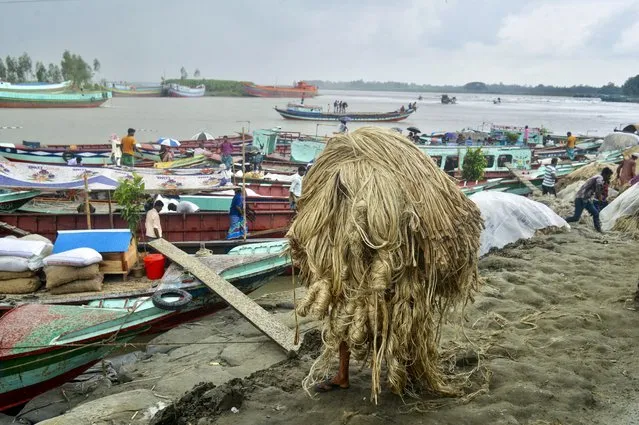 A worker carries jute to load on a boat at a rural market in Munshigonj on September 17, 2021. (Photo by Munir Uz Zaman/AFP Photo)