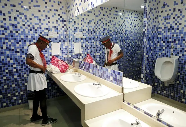Howard Jackson, a Liberian migrant, adjusts his costume in a public toilet before starting his work in the Andalusian capital of Seville, southern Spain March 15, 2016. (Photo by Marcelo del Pozo/Reuters)