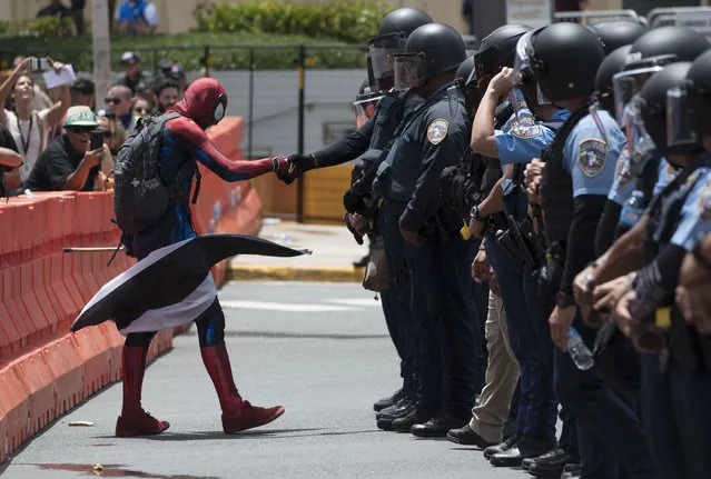 In this May 1, 2019 photo, a protester dressed as Spiderman exercises civil disobedience when crossing the perimeter established by the police during a protest against the Federal Fiscal Control Board, as part of the May Day celebration, in San Juan, Puerto Rico. The U.S. Congress established the appointed Fiscal Control Board to oversee the debt restructuring in order to combat the Puerto Rican government-debt crisis. (Photo by Carlos Giusti/AP Photo)