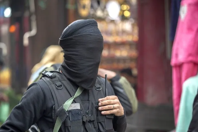 A member of Special Operations Group (SOG) of Jammu and Kashmir police, his face covered, arrives for a surprise check operation in a busy market in Srinagar, Indian controlled Kashmir, Thursday, November 11, 2021. (Photo by Mukhtar Khan/AP Photo)