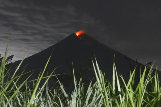 Mount Semeru releases volcanic materials during an eruption as seen from Lumajang district, East Java province, Indonesia, Tuesday, December 7, 2021. The highest volcano on Java island spewed thick columns of ash into the sky in a sudden eruption Saturday triggered by heavy rains. Villages and nearby towns were blanketed by tons of volcanic debris. (Photo by Hendra Permana/AP Photo)