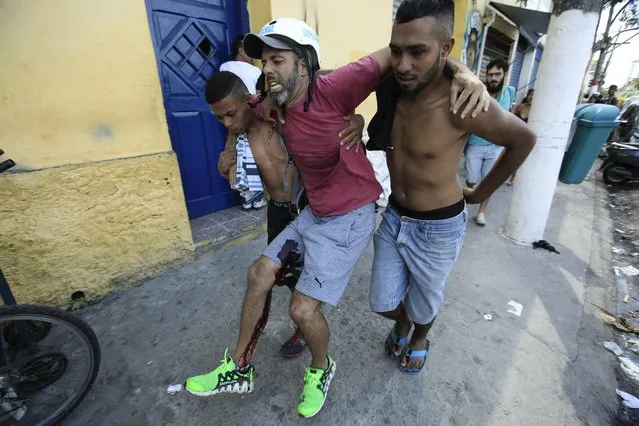 Bystanders help press photographer Dario Oliveira (C), who was wounded during a clash between military police and drug addicts in central Sao Paulo, Brazil, 23 February 2017. Oliveira suffered a gunshot wound to the leg and was reported in stable condition by a spokesman for the Military police. (Photo by Sebastiao Moreira/EPA)