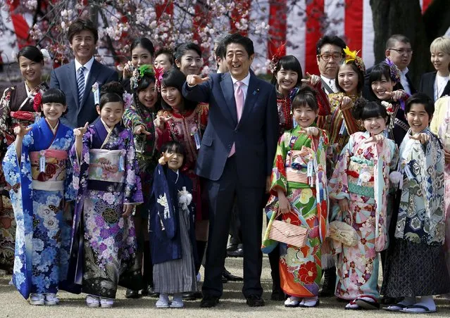 Japan's Prime Minister Shinzo Abe (C) poses with child actors, members of Japanese idol group Momoiro Clover Z and other show-business celebrities at a cherry blossom viewing party at Shinjuku Gyoen park in Tokyo, Japan April 9, 2016. (Photo by Toru Hanai/Reuters)