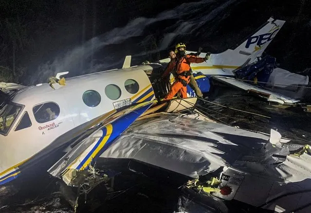 This handout picture released by Minas Gerais Fire Department shows firefighters working on the wreckage of the crashed plane where the Brazilian singer Marilia Mendonca died on the afternoon in Caratinga, Brazil, on November 5, 2021. The young Brazilian singer Marilia Mendonca, one of the most popular of the “sertanejo” genre in Brazil, died this Friday along with four other people in a plane crash in the state of Minas Gerais, the firefighters confirmed. (Photo by Minas Gerais Fire Department/AFP Photo)