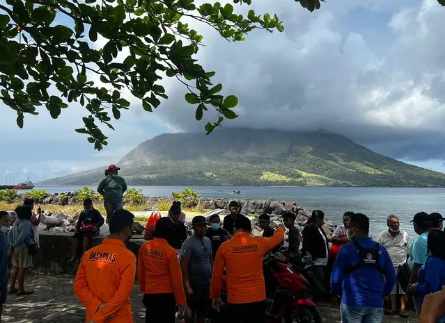 A handout photo made available by National Search and Rescue Agency (BASARNAS) shows people and members of the National Search and Rescue Agency looking at smoke and ash erupting from Mount Ruang, as seen from Sitaro, Indonesia, 17 April 2024. The Center for Volcanology and Geological Disaster Mitigation (PVMBG) of the Ministry of Energy and Mineral Resources reported that Mount Ruang in the Sitaro Islands Regency, North Sulawesi, erupted on 16 April night. As a result of the eruption of Mount Ruang, 272 families, or around 828 people, were evacuated. (Photo by BASARNAS/EPA)