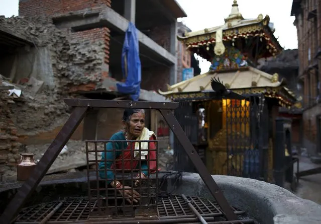 A woman fetches water from a well near collapsed house, a month after the April 25 earthquake  in Kathmandu, Nepal May 25, 2015. (Photo by Navesh Chitrakar/Reuters)