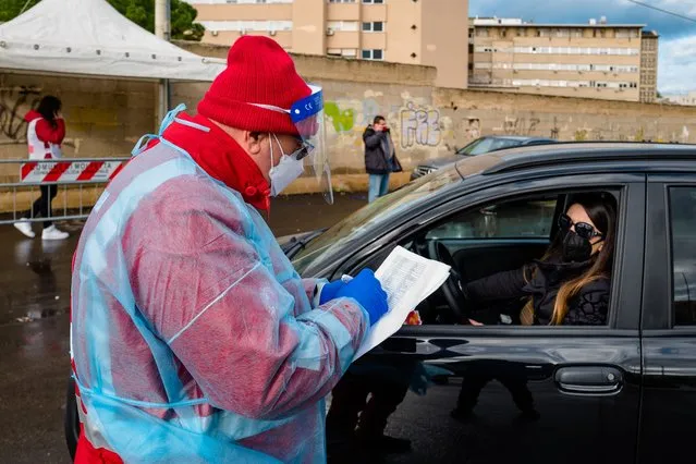 A Croce Rossa volunteer checks the name of the patient who has to carry out the swab in the car, at the Hospital of Molfetta on January 2, 2021. From 9 November, at the Molfetta hospital, the drive through station (on board the car) is always active for swabs with the collaboration of volunteers who facilitate and order the traffic of cars with positive patients or patients who have have already been quarantined at home and are waiting for the last swab which certifies recovery from the virus. With the increase in the number of Covid-19 cases, waiting times for those who need to carry out swabs have significantly reduced. (Photo by Davide Pischettola/NurPhoto via Getty Images)