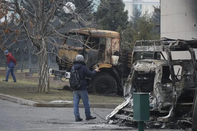A man photographs a bus, which was burned during clashes in Almaty, Kazakhstan, Tuesday, January 11, 2022. (Photo by Vladimir Tretyakov/NUR.KZ via AP Photo)