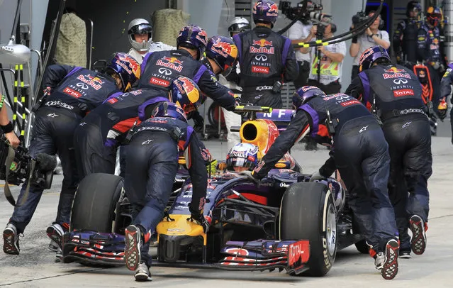 Red Bull Formula One driver Daniel Ricciardo of Australia has his car pushed back to the garage during the Malaysian F1 Grand Prix at Sepang International Circuit outside Kuala Lumpur, March 30, 2014. Ricciardo was handed a 10 place grid penalty for next week's Bahrain Grand Prix after Formula One stewards ruled he had left the pits in an unsafe manner in Sunday's Malaysian race. (Photo by Peter Lim/Reuters)