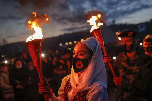 Kosovar Albanians in traditional and military costumes hold torches during the bonfire night to mark the 23rd anniversary of Kosovo Liberation Army (KLA) Commander Adem Jashari death, in the village of Prekaz, Kosovo, 07 March 2021. KLA Commander Adem Jashari was killed in 1998 along with 45 members of his family by Serb Security forces in village of Prekaz, some 40km west of Kosovo's capital Pristina, sparking a full-blown rebel insurgency. (Photo by Valdrin Xhemaj/EPA/EFE)