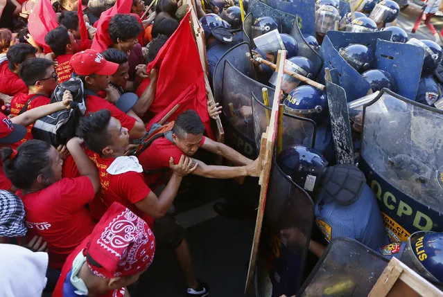 Protesters, mostly workers, clash with riot police as they try to force their way closer to the gates of the US Embassy in Manila to mark the International Labor Day Sunday, May 1, 2016 in Manila, Philippines. The protesters are demanding among others, better wages and salaries, an end to contractual labor, better working conditions and retirement benefits, less taxes, public and not privatized social services, and the assertion of national sovereignty against foreign domination and control. (Photo by Bullit Marquez/AP Photo)