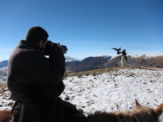 Photographer Asher Svidensky, holding the camera, taking a shot of a one of the Eagle hunters fathers whilst on horseback, proudly displaying his eagle on his arm. (Photo by Asher Svidensky/Caters News)