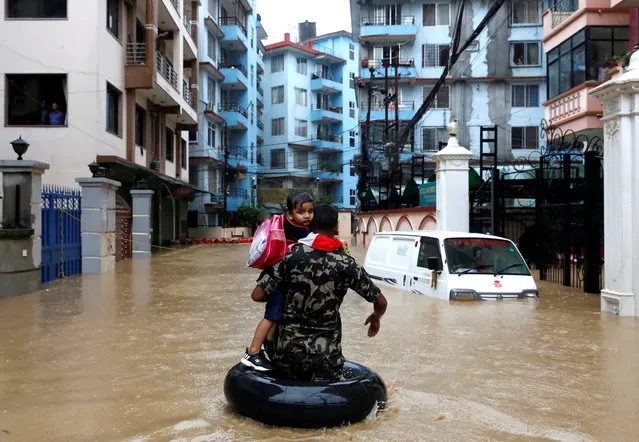 A member of Nepalese army carrying a child walks along the flooded colony in Kathmandu, Nepal on July 12, 2019. (Photo by Navesh Chitrakar/Reuters)