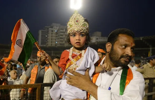 An Indian supporter of Chief Minister of the Indian state of Gujarat and Bharatiya Janata Party (BJP) prime ministerial candidate Narendra Modi holds his daughter, dressed in a Bharatha Matha (Mother of India) costume, during an election rally for the BJP and allied parties in Hyderabad on April 22, 2014. India's 814-million-strong electorate is voting in the world's biggest election which is set to sweep the Hindu nationalist opposition to power at a time of lowgrowth, anger about corruption and warnings about religious unrest. (Photo by Noah Seelam/AFP Photo)