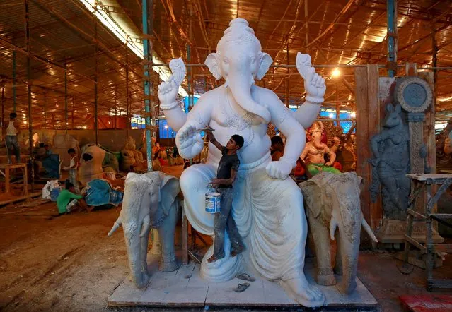 An artisan works on an idol of Hindu elephant god Ganesh, the deity of prosperity, at a workshop in Mumbai, India, July 2, 2015. Idols of Ganesh are made two to three months before Ganesh Chaturthi, a popular religious festival in India. During the festival the idols will be taken through the streets in a procession accompanied by dancing and singing, and to be immersed in a river or the sea in accordance with the Hindu faith. (Photo by Danish Siddiqui/Reuters)