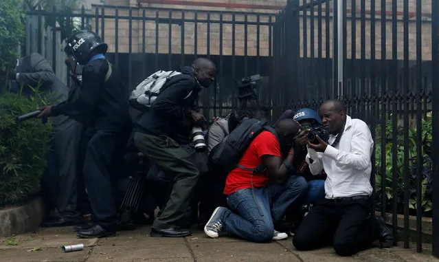 Journalists and riot-police take cover after riot police lobbed teargas canisters to disperse members of the opposition Coalition for Reforms and Democracy (CORD), during a protest at the premises hosting the headquarters of Independent Electoral and Boundaries Commission (IEBC) to demand the disbandment of the electoral body ahead of next year's election in Nairobi, Kenya, May 9, 2016. (Photo by Thomas Mukoya/Reuters)