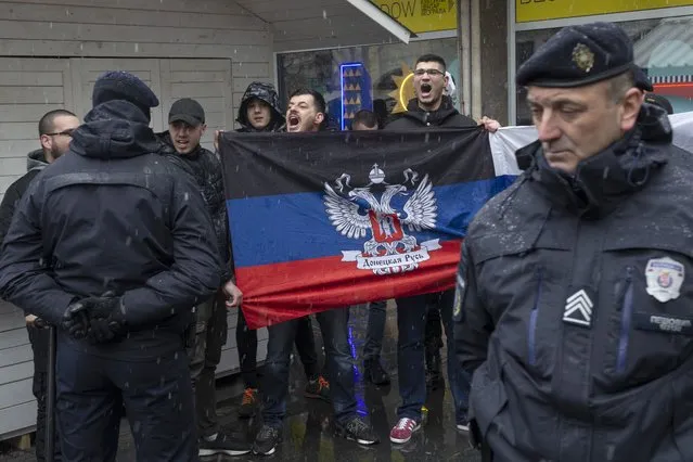 People hold the flag of the breakaway Donetsk People's Republic as they try to disrupt a protest against the Russian military invasion of Ukraine, in Belgrade, Serbia, Sunday, March 6, 2022. (Photo by Marko Drobnjakovic/AP Photo)