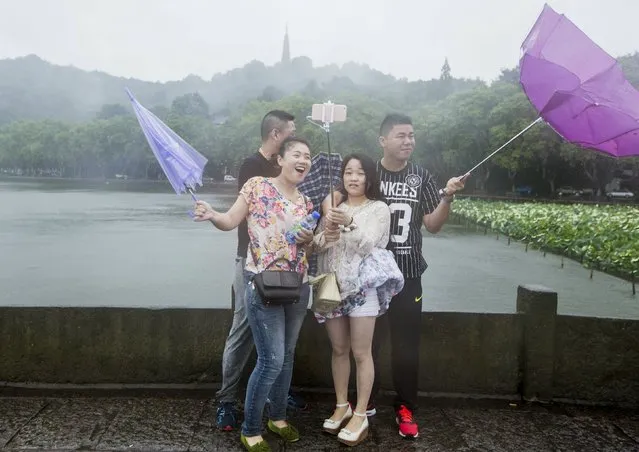 Tourists hold umbrellas as they take a picture with a selfie stick next to the West Lake against strong wind under the influence of Typhoon Chan-hom, in Hangzhou, Zhejiang province, China, July 11, 2015. (Photo by Reuters/Stringer)