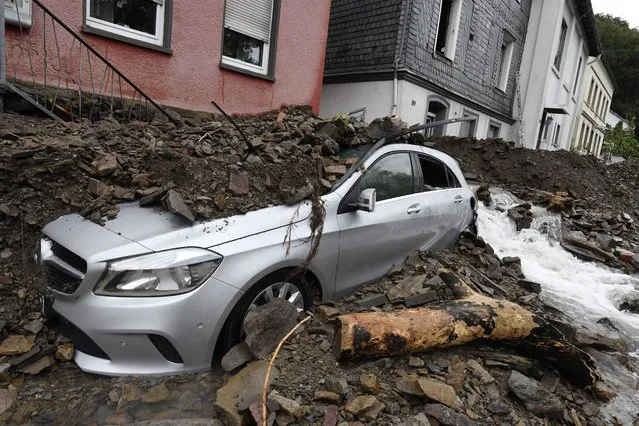 A car is covered in Hagen, Germany, Wednesday, July 15, 2021 with the debris brought by the flooding of the “Nahma” river the night before. The heavy rainfalls had turned the small river into a raging torrent. (Photo by Roberto Pfeil/dpa via AP Photo)