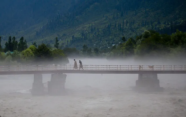 Kashmiri Muslims walk over a bridge as they inspect water level near Kullan, some 70 Kilometers (43.75 miles) northeast of Srinagar, Indian controlled Kashmir, Friday, July 17, 2015. Flash flood and cloudbursts in Indian Kashmir killed several people and damaged dozens of residential houses and shops according to reports. (Photo by Dar Yasin/AP Photo)