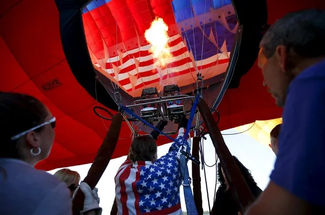 A pilot fills a hot air balloon at sunrise on day one of the 2015 New Jersey Festival of Ballooning in Readington, New Jersey, July 24, 2015. (Photo by Mike Segar/Reuters)