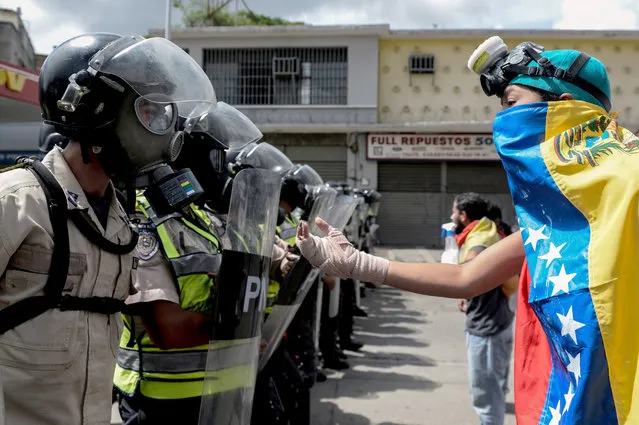 A Venezuelan opposition activist faces police agents during a march against President Nicolas Maduro, in Caracas on May 1, 2017. Security forces in riot vans blocked off central Caracas Monday as Venezuela braced for pro- and anti-government May Day protests one month after a wave of deadly political unrest erupted. (Photo by Federico Parra/AFP Photo)