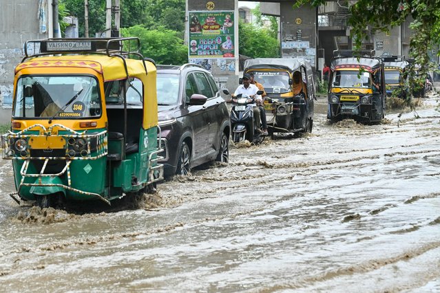 Commuters wade through a street after heavy rainfall in Amritsar on August 9, 2024. (Photo by Narinder Nanu/AFP Photo)