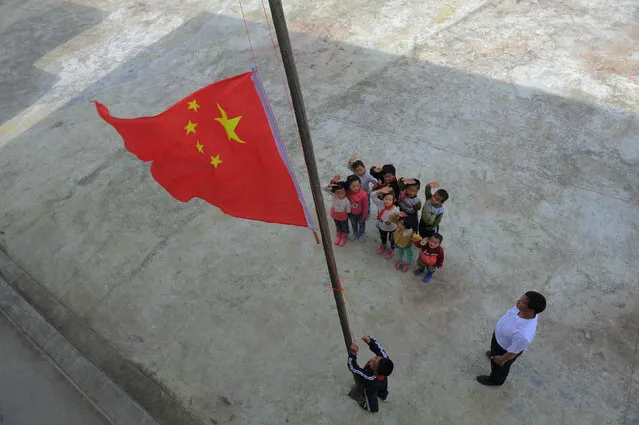 Pupils salute as they participate in a flag-raising ceremony with their teacher at a primary school in Longli county, Guizhou Province, China, May 31, 2016. (Photo by Reuters/Stringer)